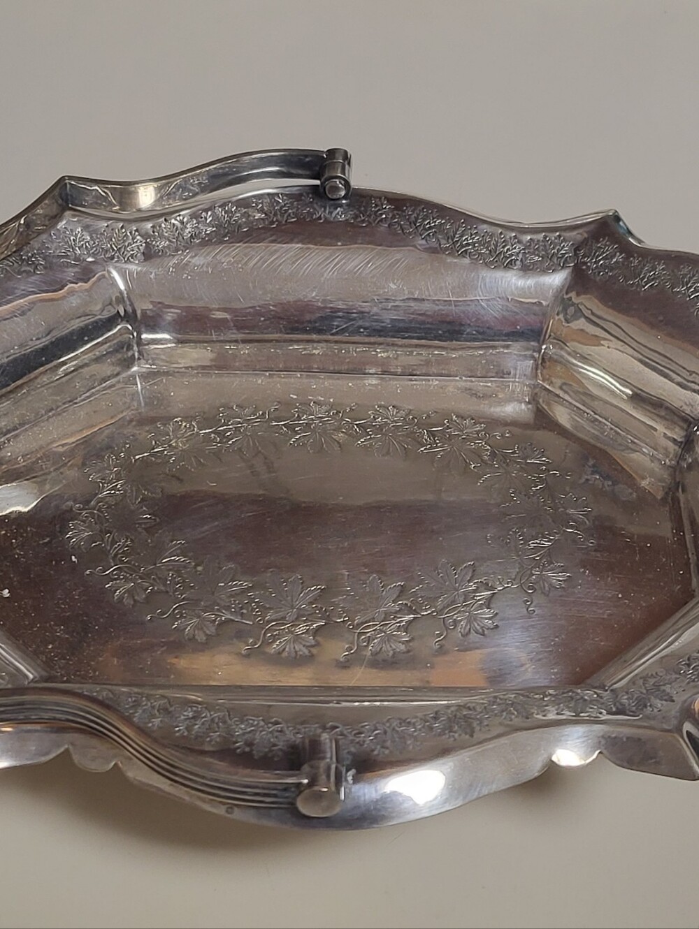 Silver-plated decorative tray with ornate scalloped rim and handles,